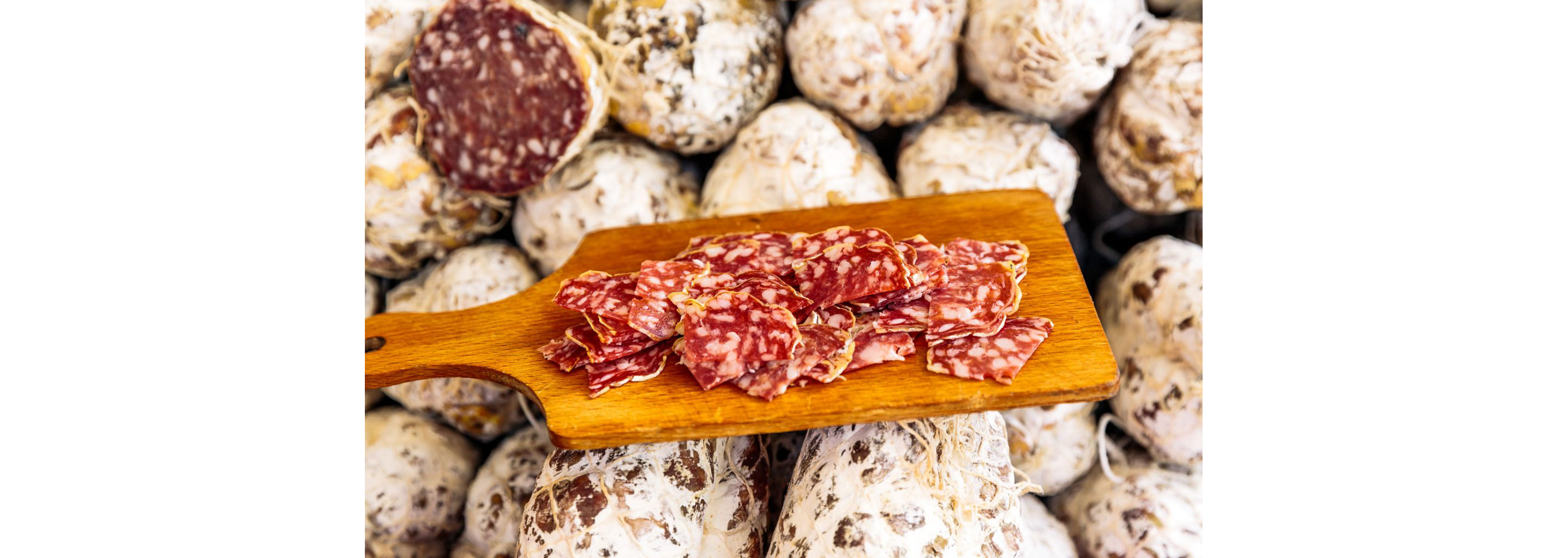 A wooden cutting board holding slices of fine meats.