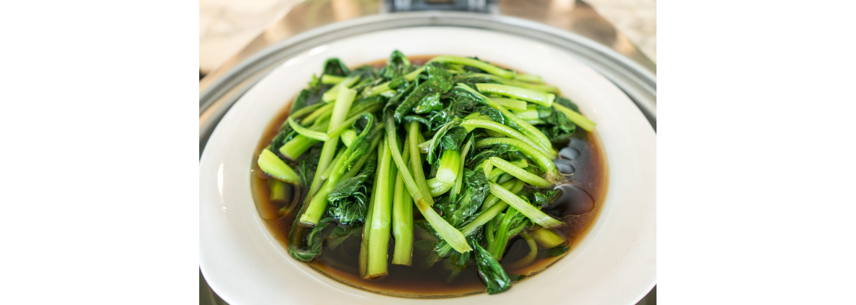 A bowl of freshly steamed greens resting in broth.