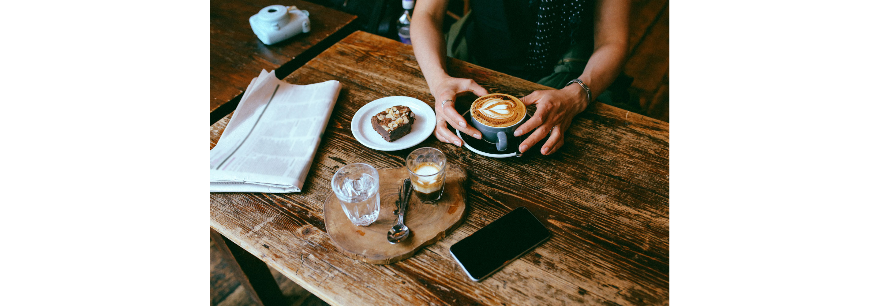 A person enjoying their intricate foam cappuccino at a coffee shop.