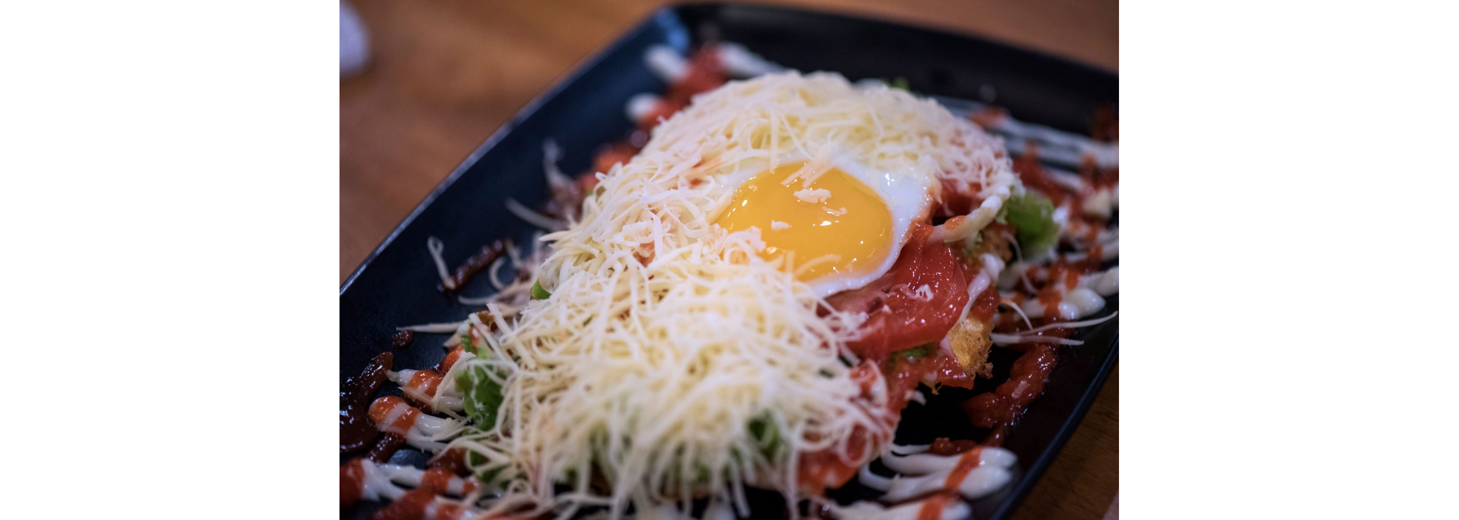 An open roti john topped with cheese and an egg.