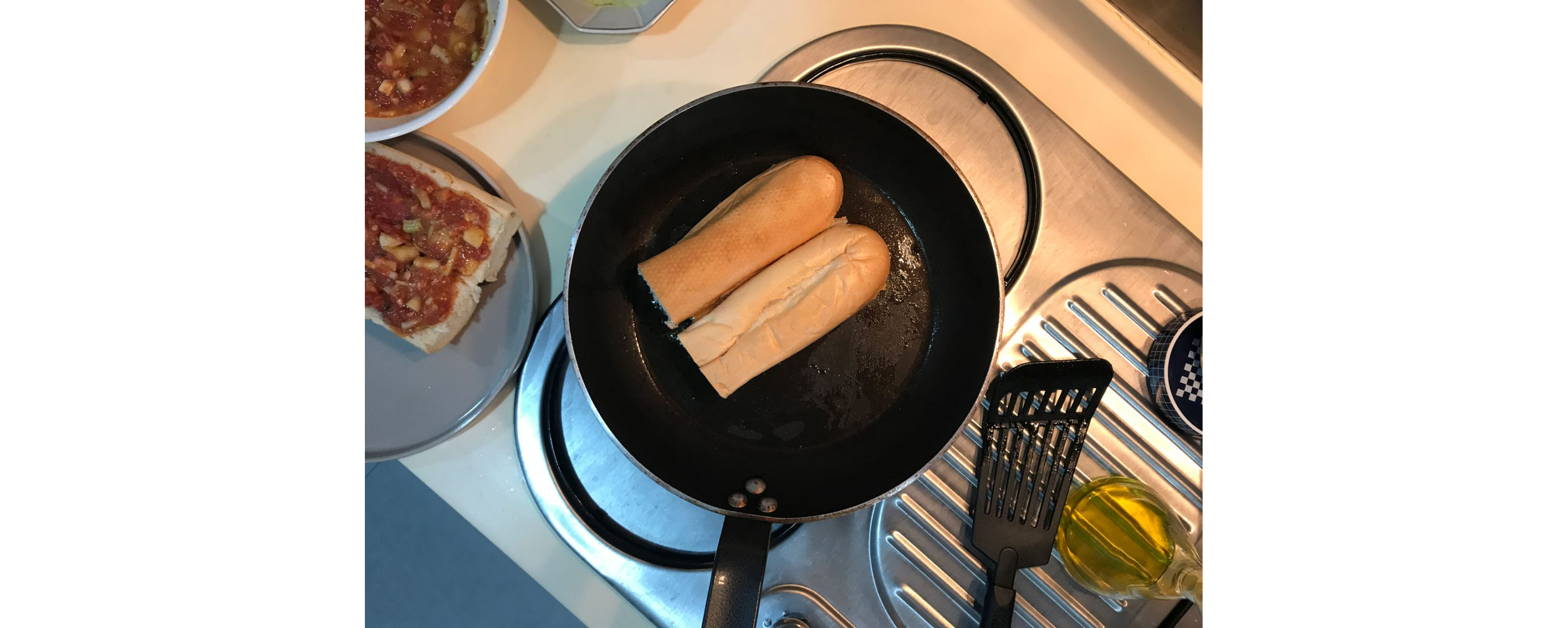 Two halved loaves toasting in a black skillet.