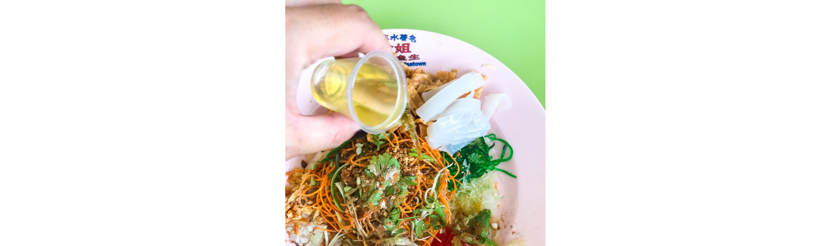 Someone pouring sesame oil on yusheng.