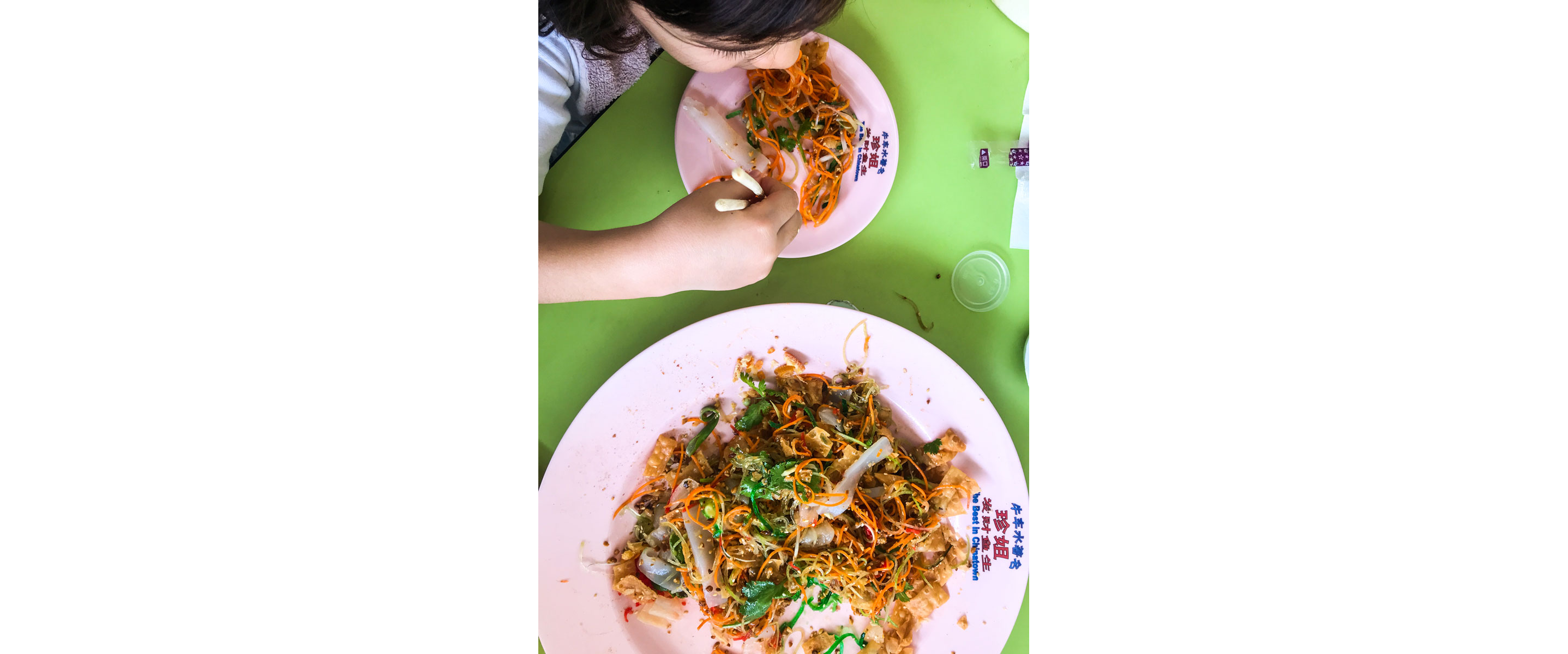 Someone taking a portion from a bowl of yusheng.