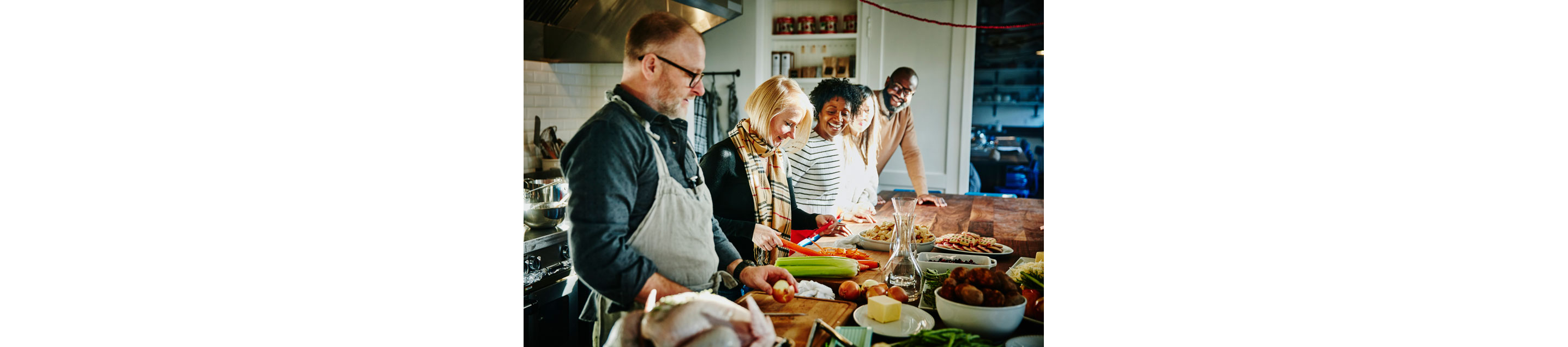 A family gathered in the kitchen preparing dinner.