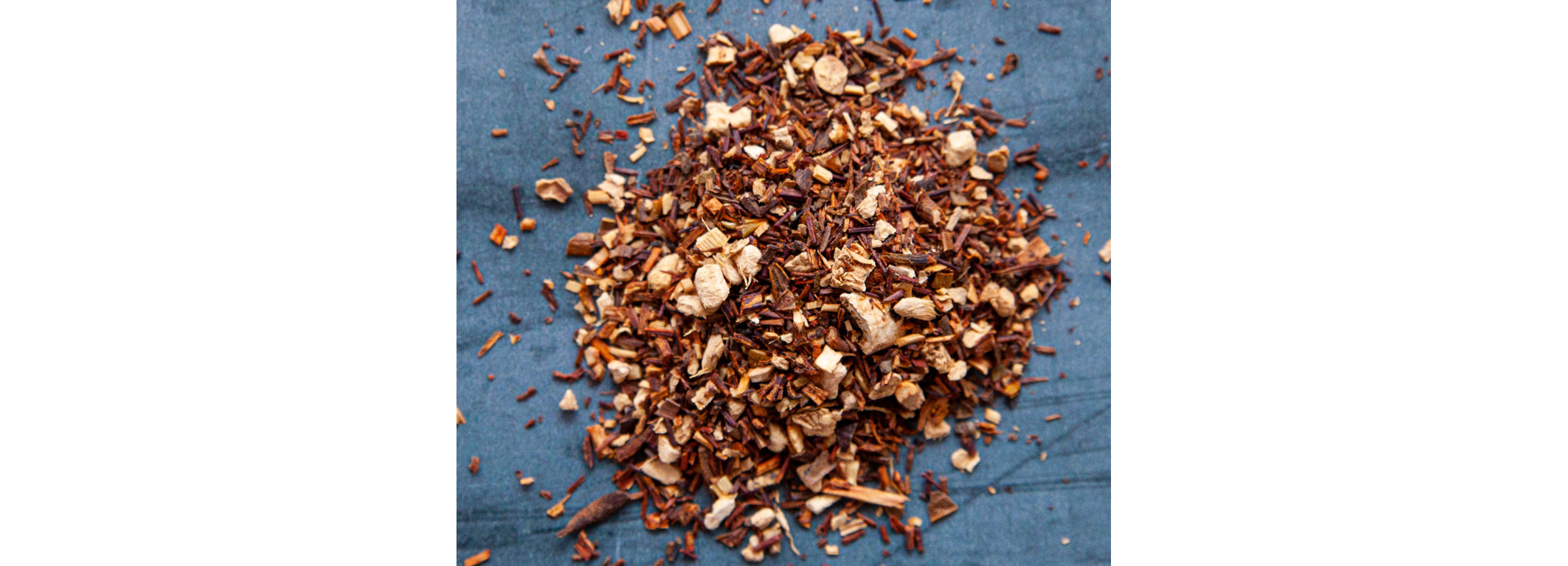 A pile of various tea leaves resting on a blue table.