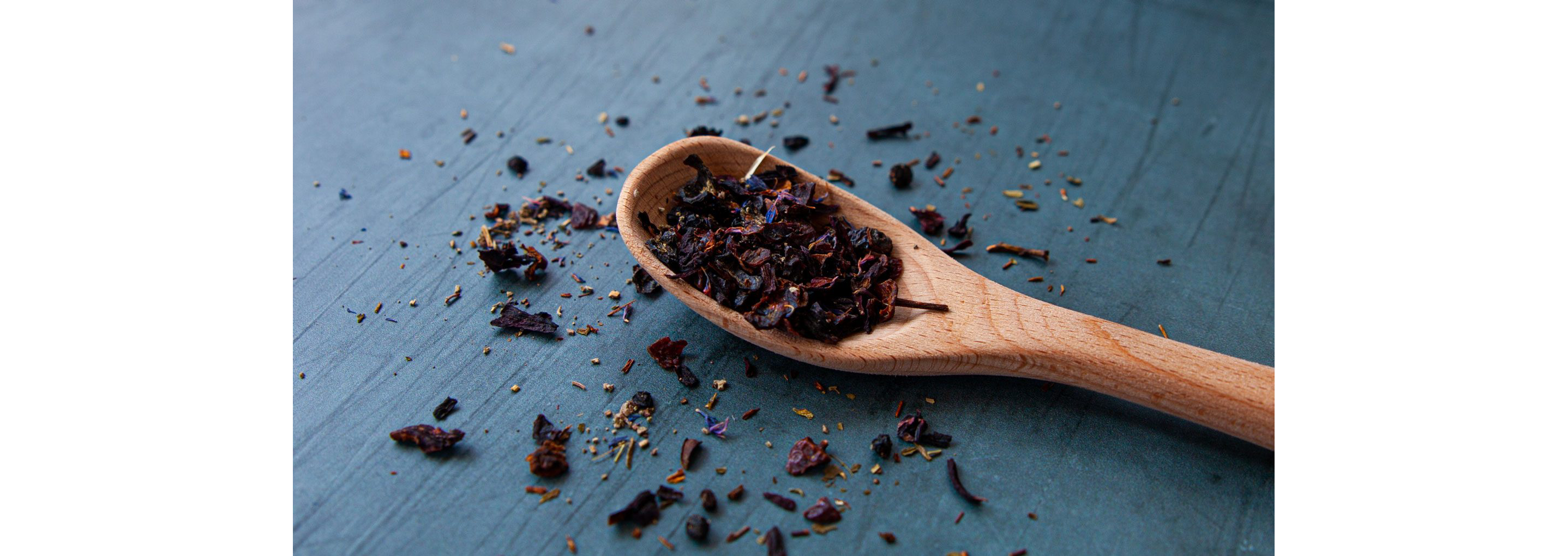 A wooden spoon filled with dried black tea leaves.