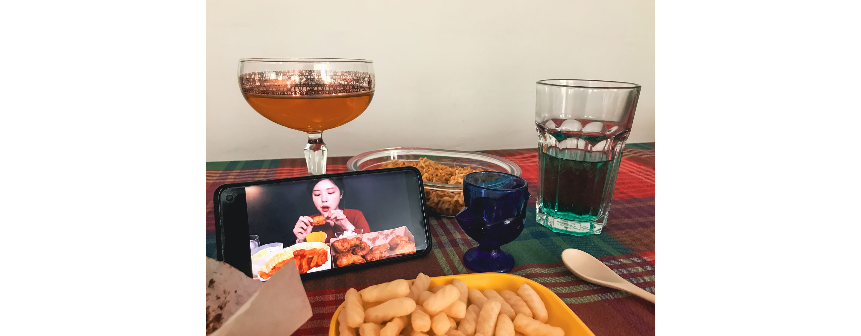 Food for one and a smart phone displaying a person eating.