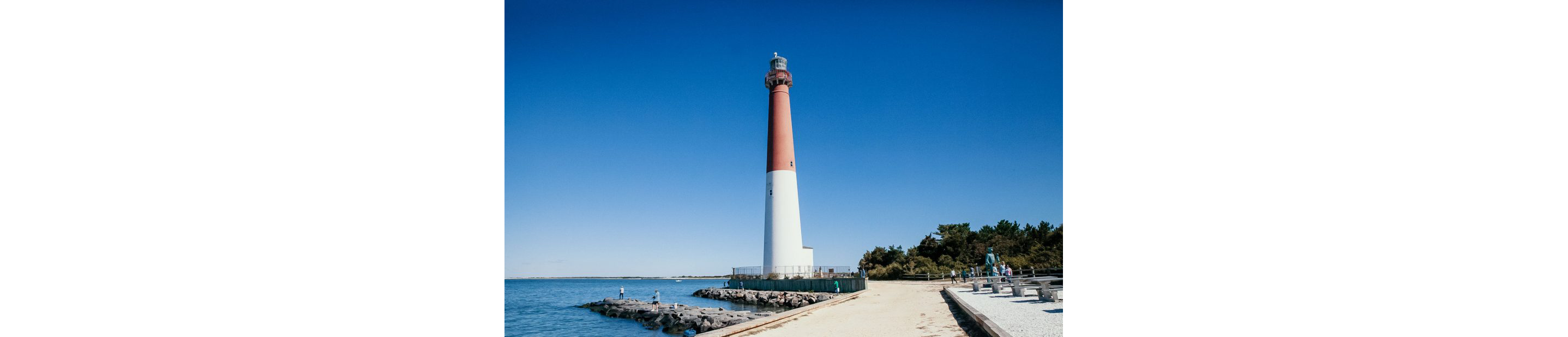 A bold lighthouse resting under a clear blue sky.