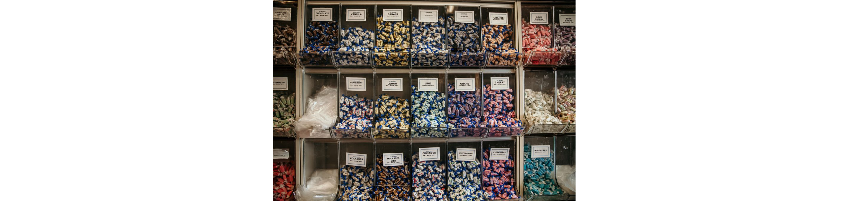 Individual tubs labeled and filled with a variety of salt water taffy flavors.
