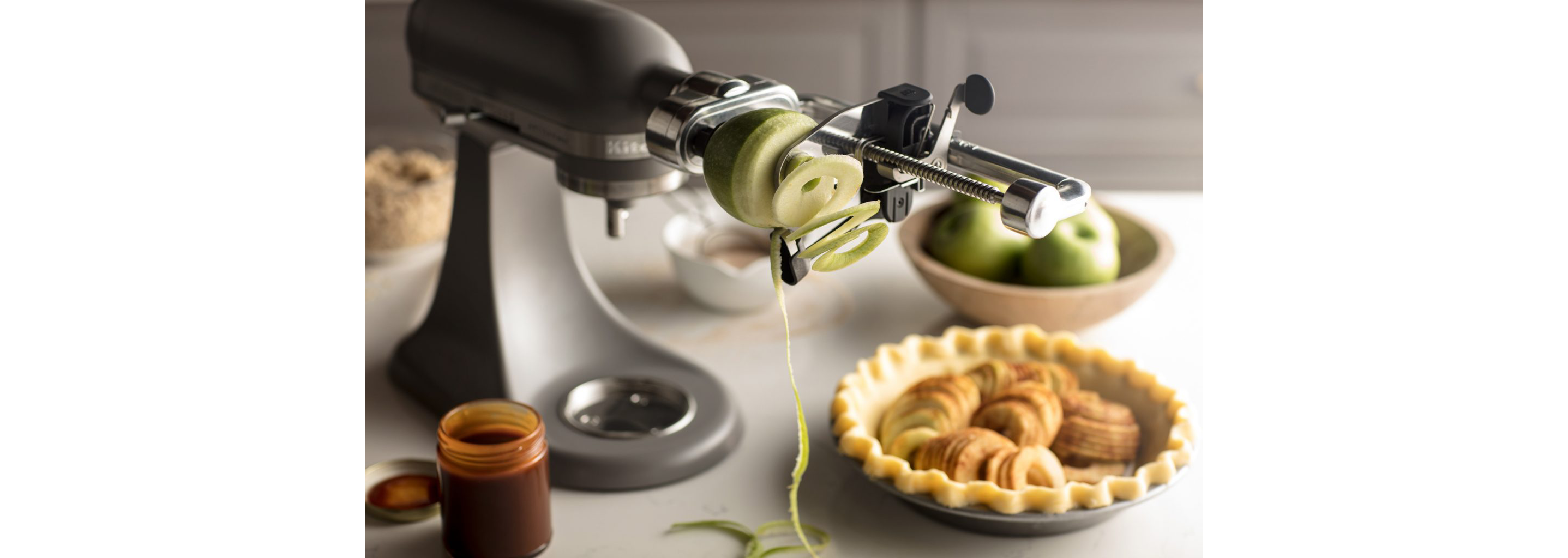 A KitchenAid® stand mixer spiralizing a green apple.