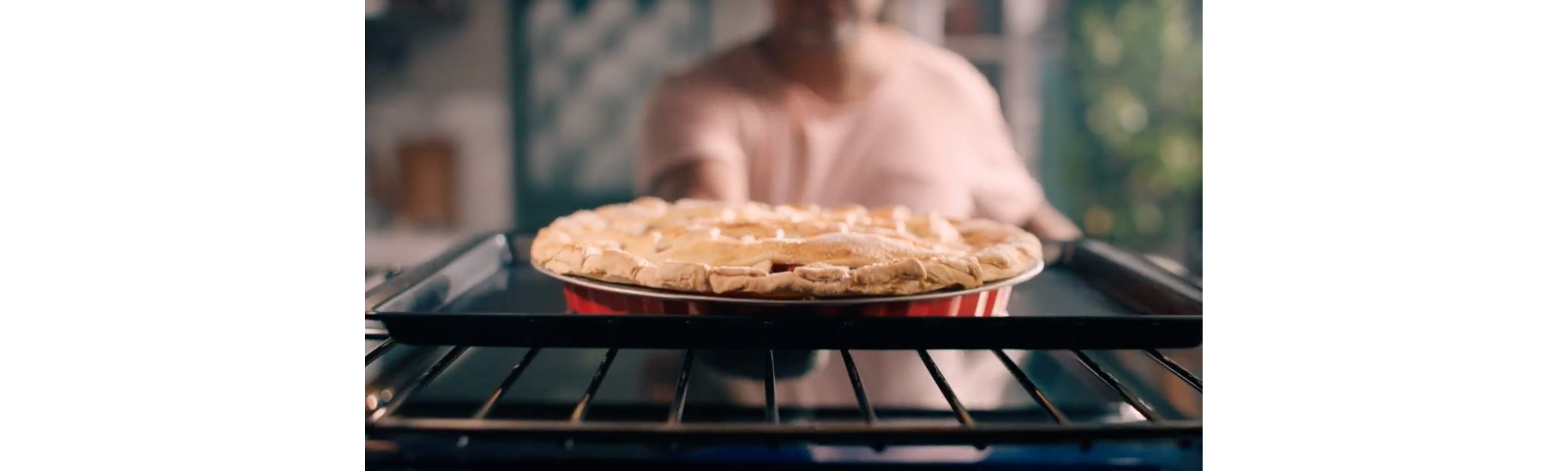 A person pulling out a pie from the oven.