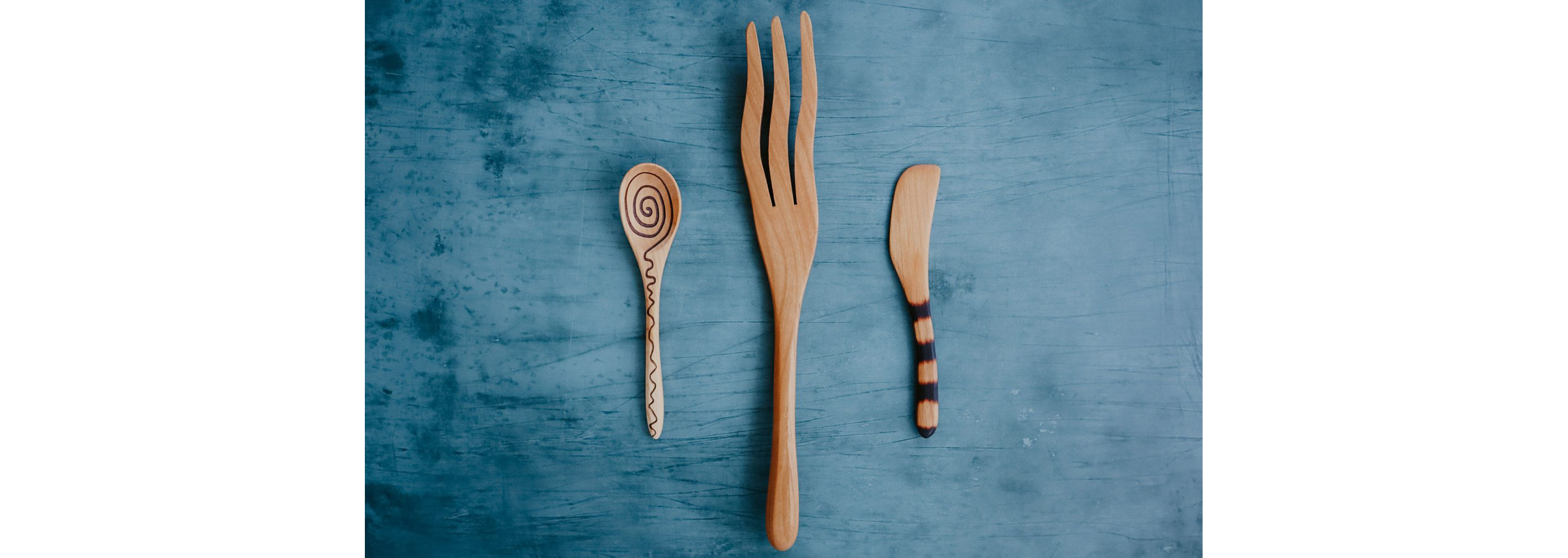 A uniquely designed wooden spoon, fork and knife.