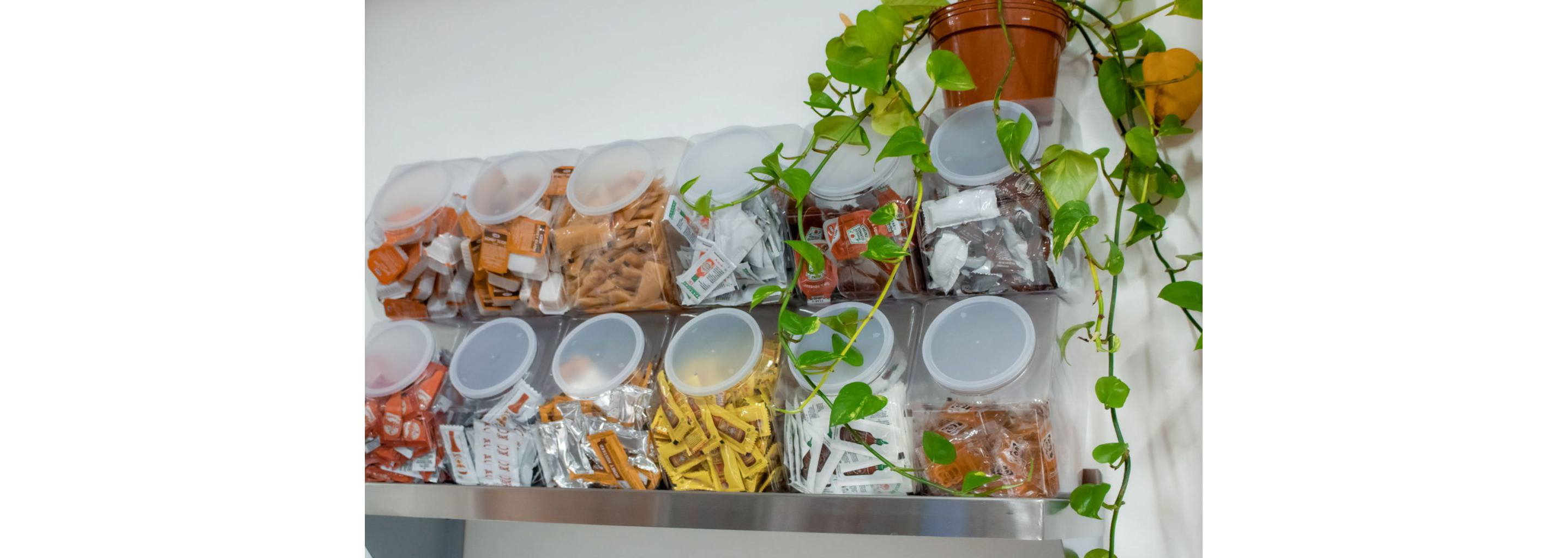 Individual storage containers filled with a variety of sauce packets and containers.