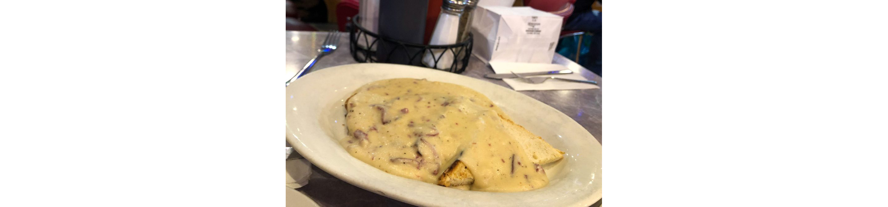 A large white dish of chipped beef topped with creamy white sauce.