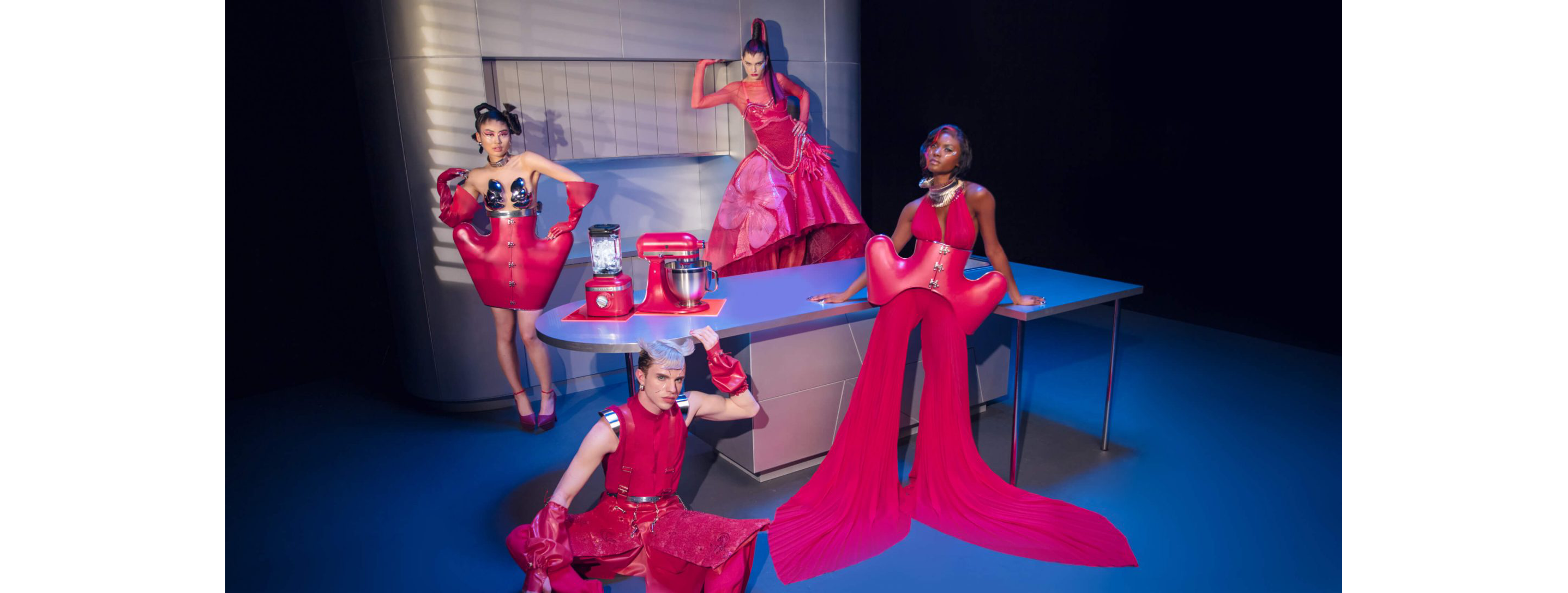  Four models dressed in Hibiscus Collection designs in a chrome kitchen with the Hibiscus stand mixer and blender.