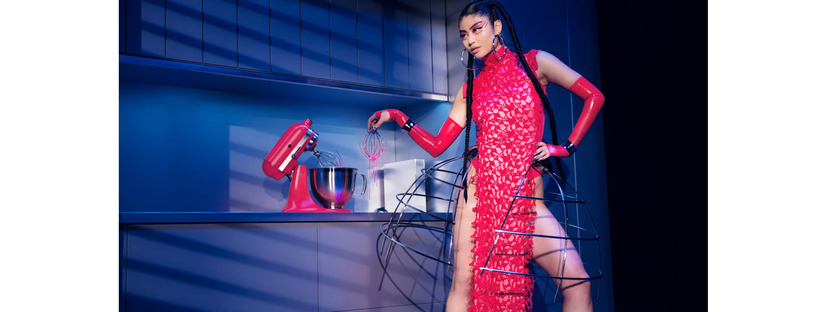 A model dressed in Marta Del Rio’s New York Fashion Week Collection posing in a kitchen with the KitchenAid® Artisan® Series Stand Mixer in Hibiscus.