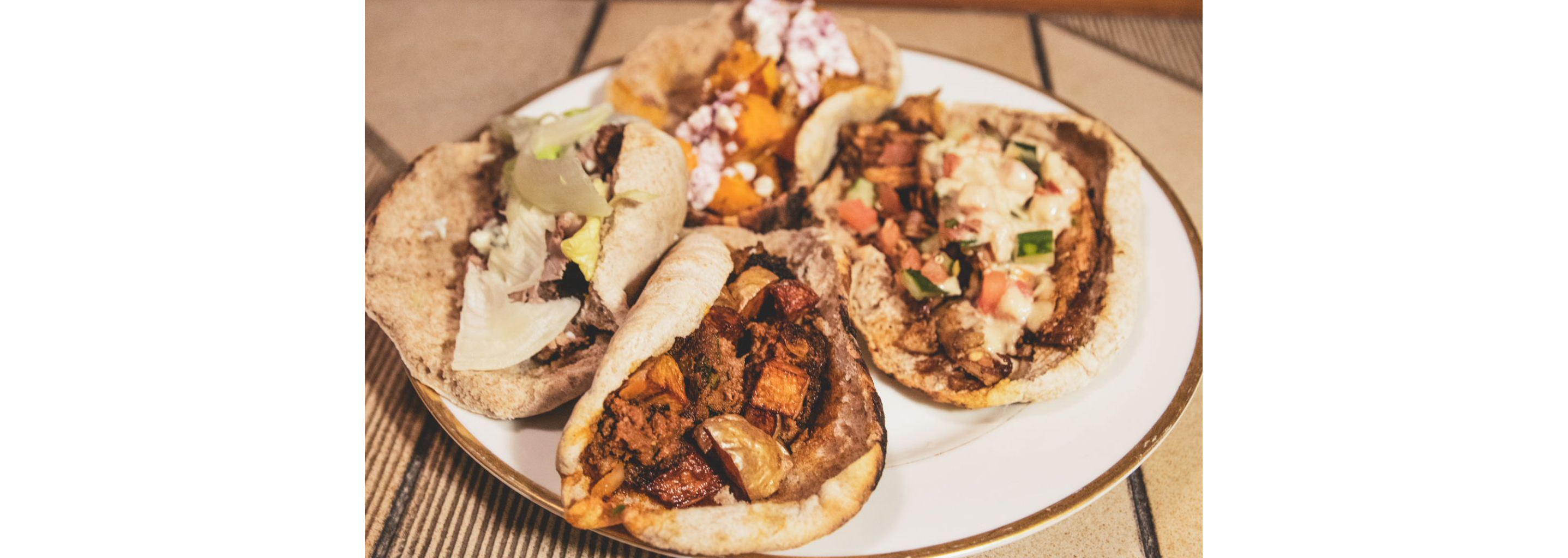 A plate filled up with a variety of different shwarma wraps.