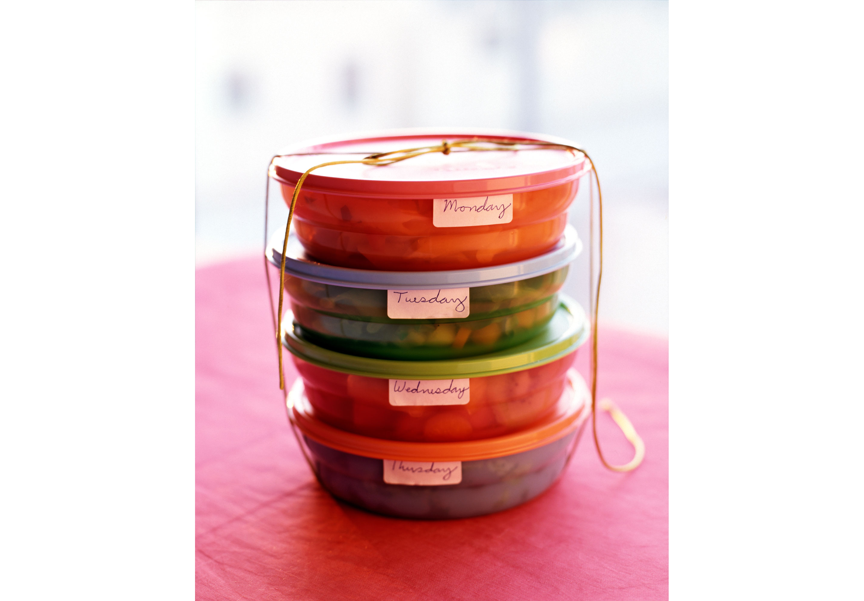 Four stacked food containers labeled with days of the week.
