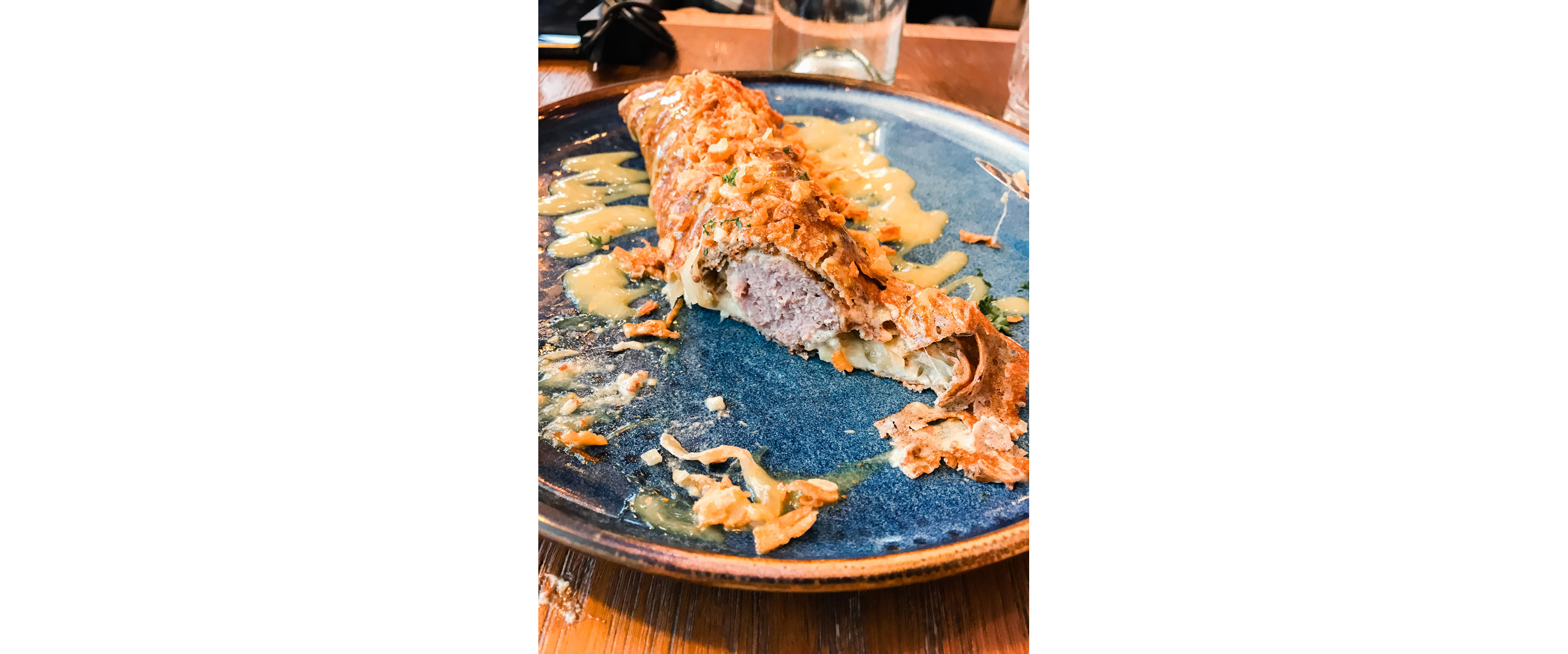 A crispy galette-saucisse drizzled in sauce.