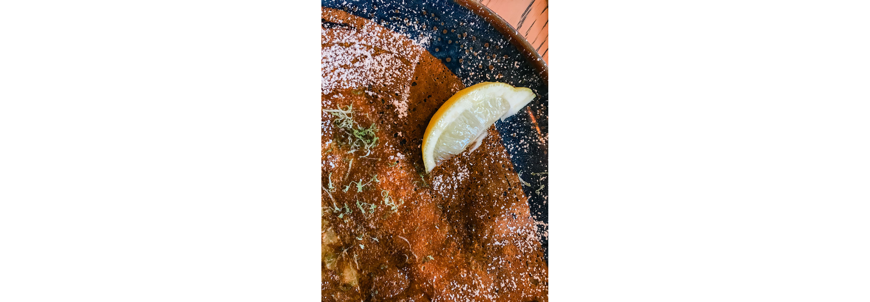 A crispy crepe with a slice of lemon.