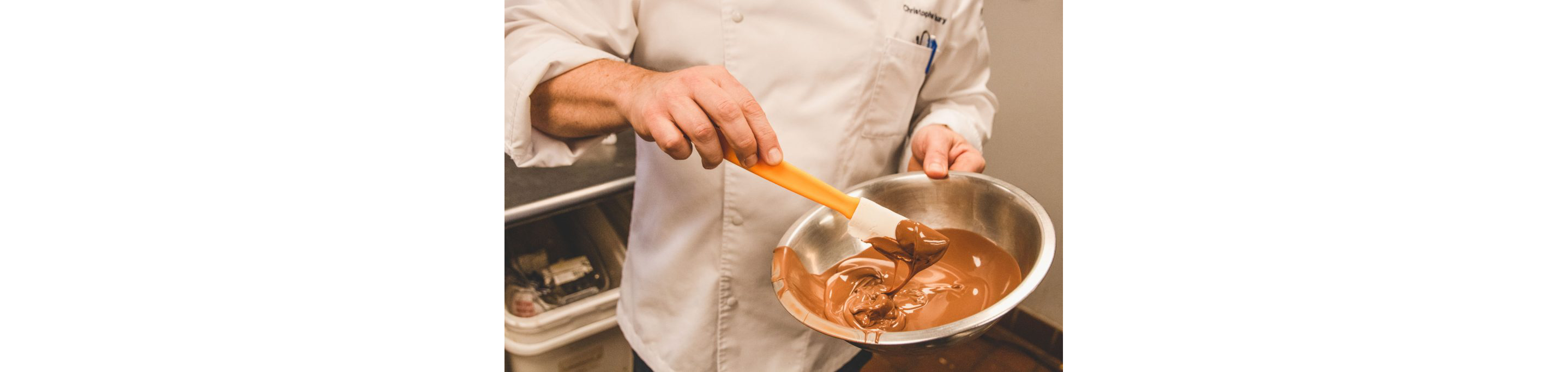 Chef Christophe Toury mixing a bowl of chocolate with a spatula.