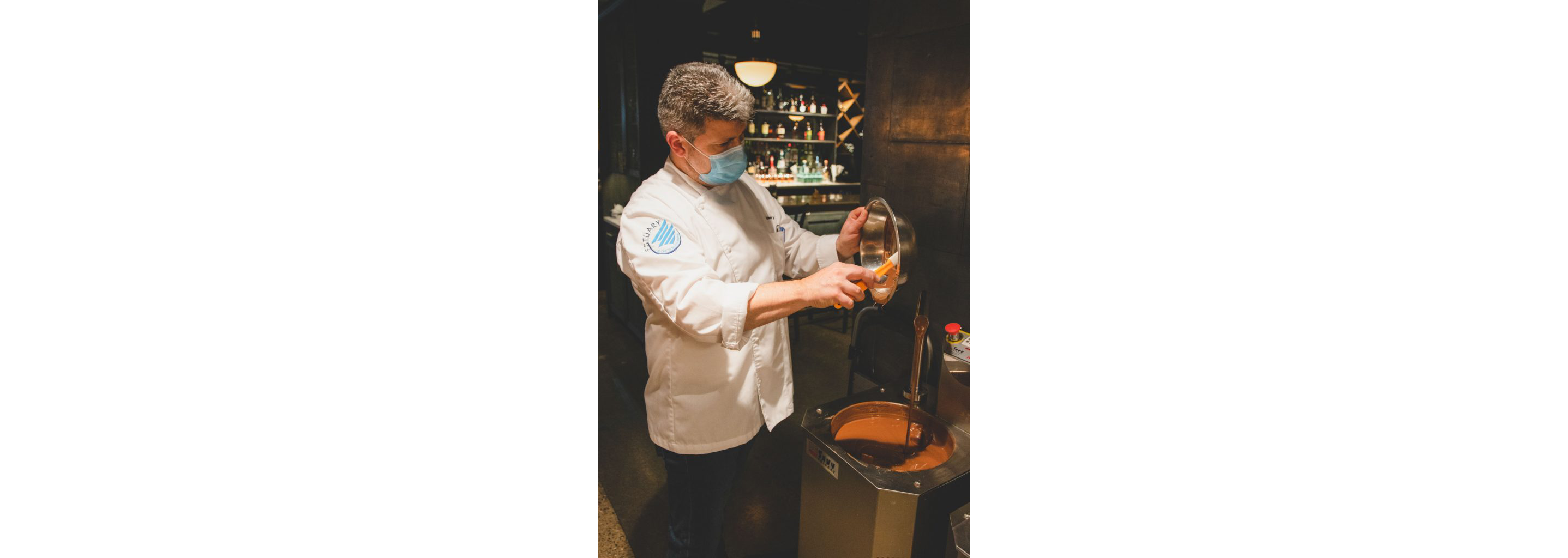 Chef Christophe Toury gently scraping a bowl filled with chocolate.