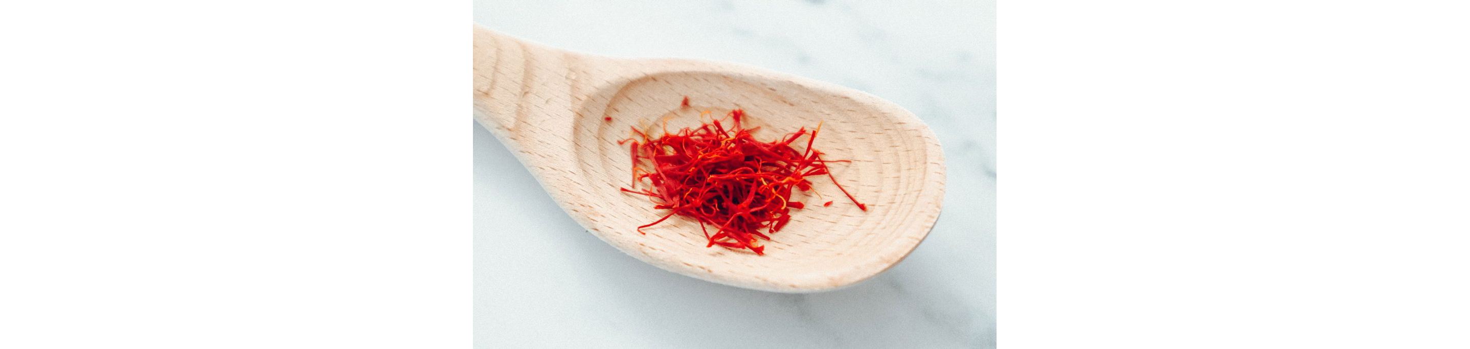 A large wooden spoon holding saffron.