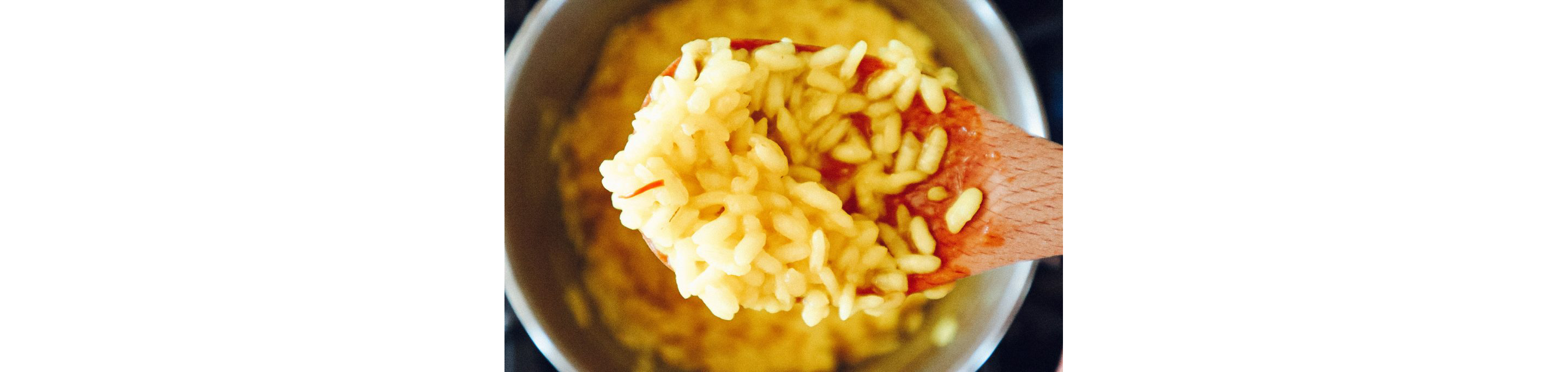 A wooden spoon holding basmati rice.