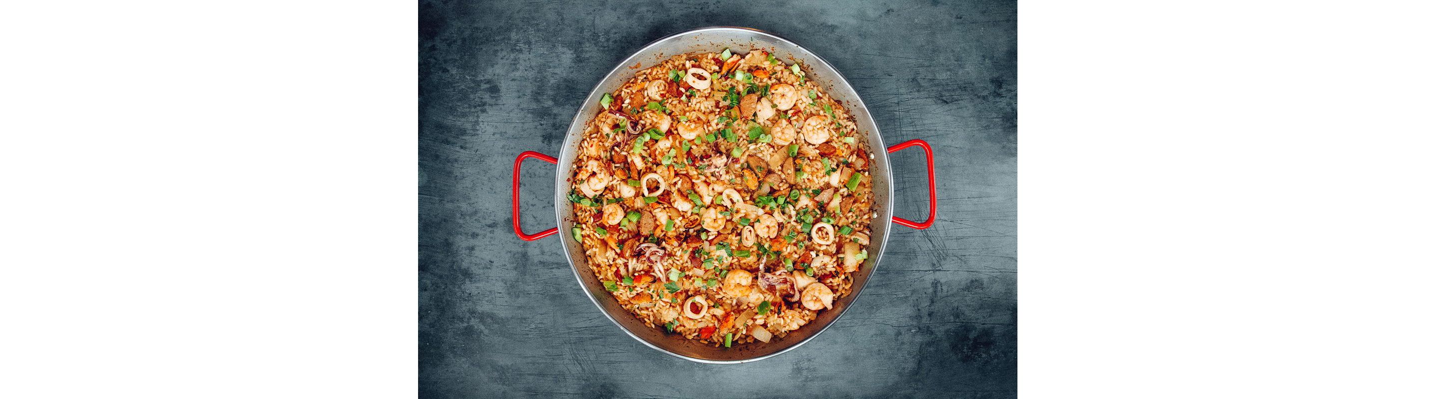 A large red pot filled with shrimp jambalaya.