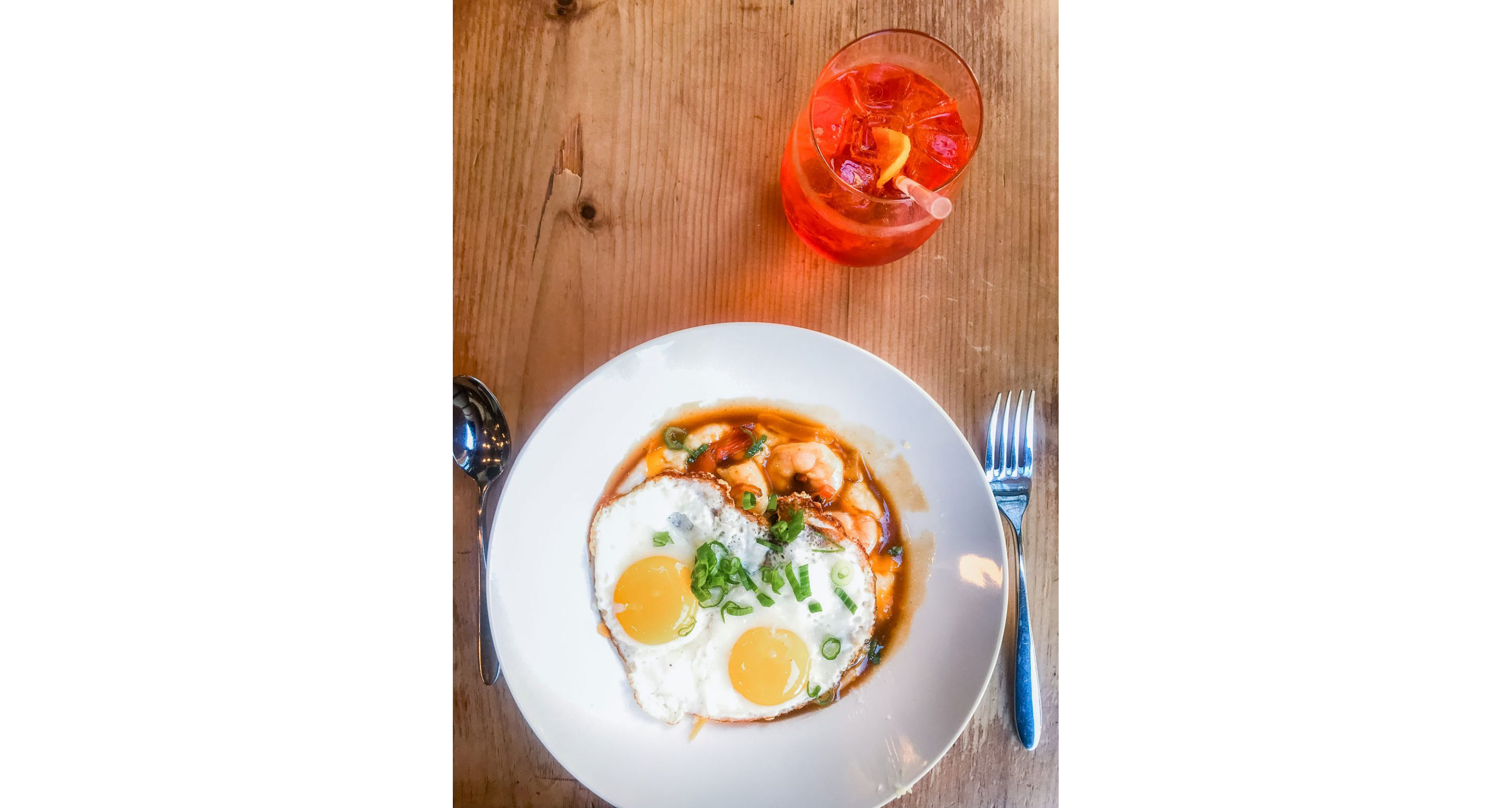A fried egg resting on top of a bowl of shrimp and grits.