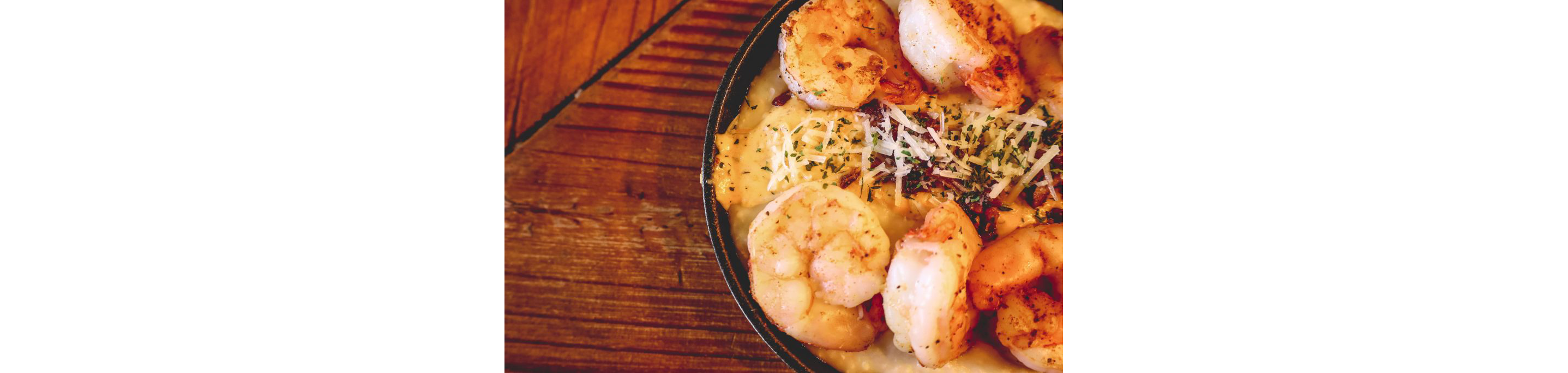 A closeup of a cast iron skillet filled with shrimp and grits.