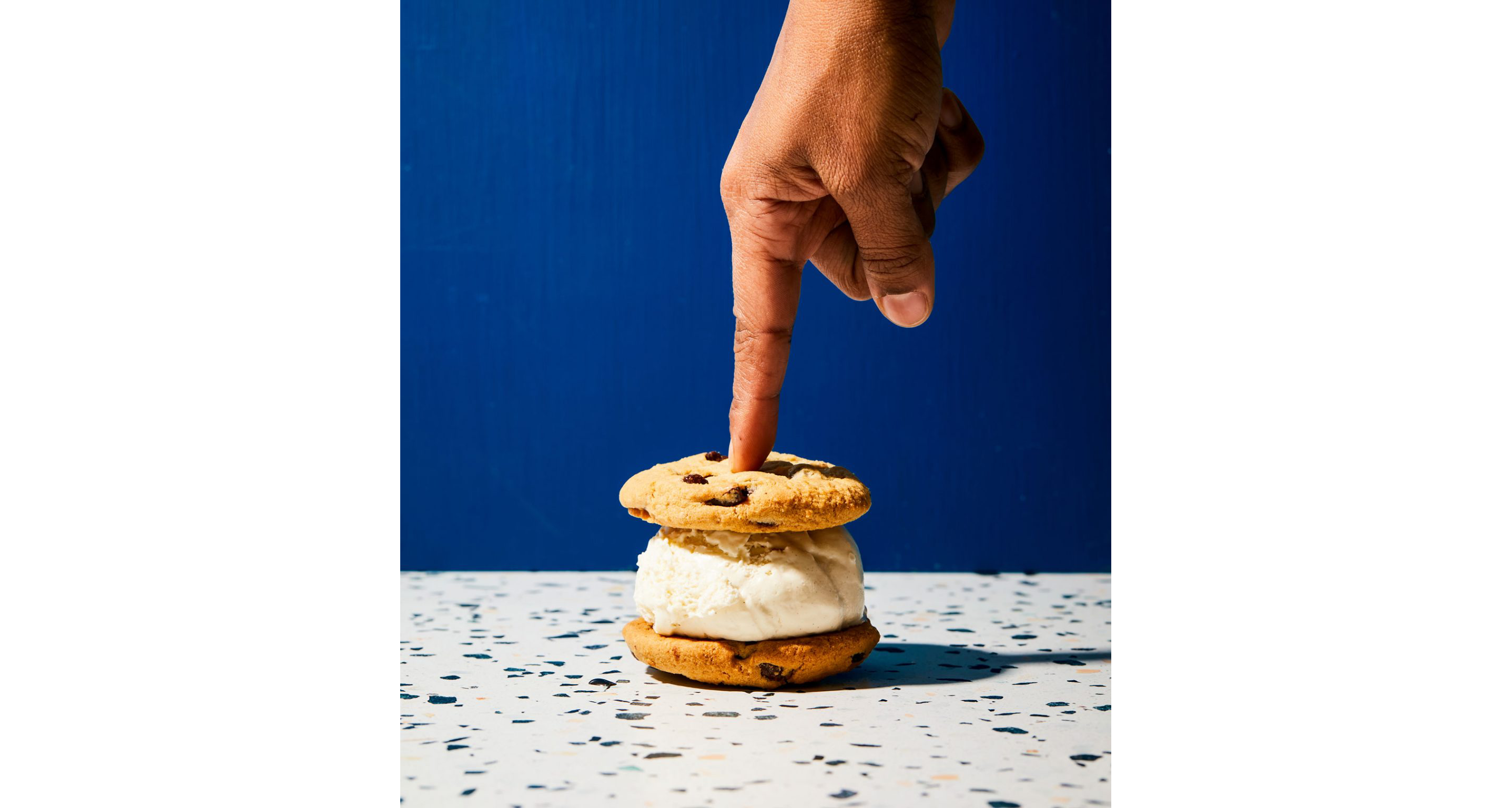 A person pressing on an ice cream sandwich.