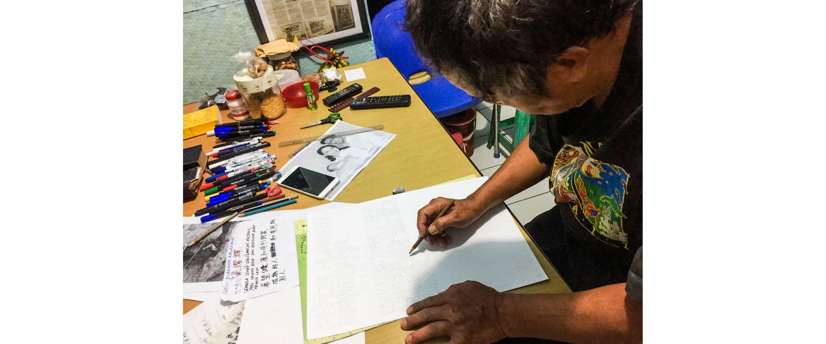Paulus Supomo sketching his artwork with a pencil.