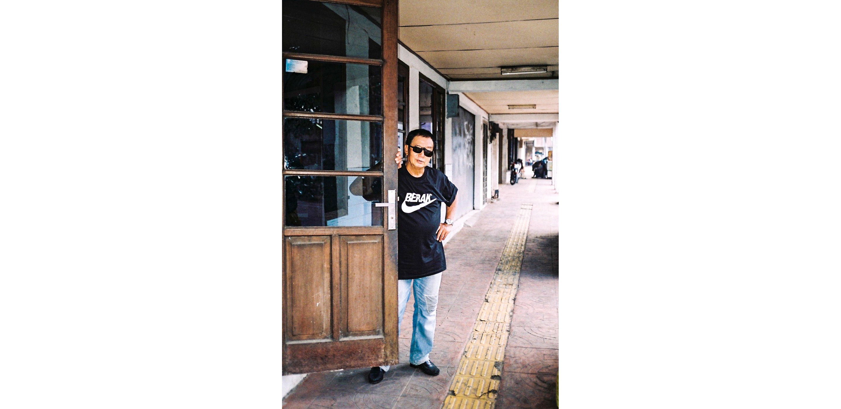 Paulus Supomo in black sunglasses holding a door open.