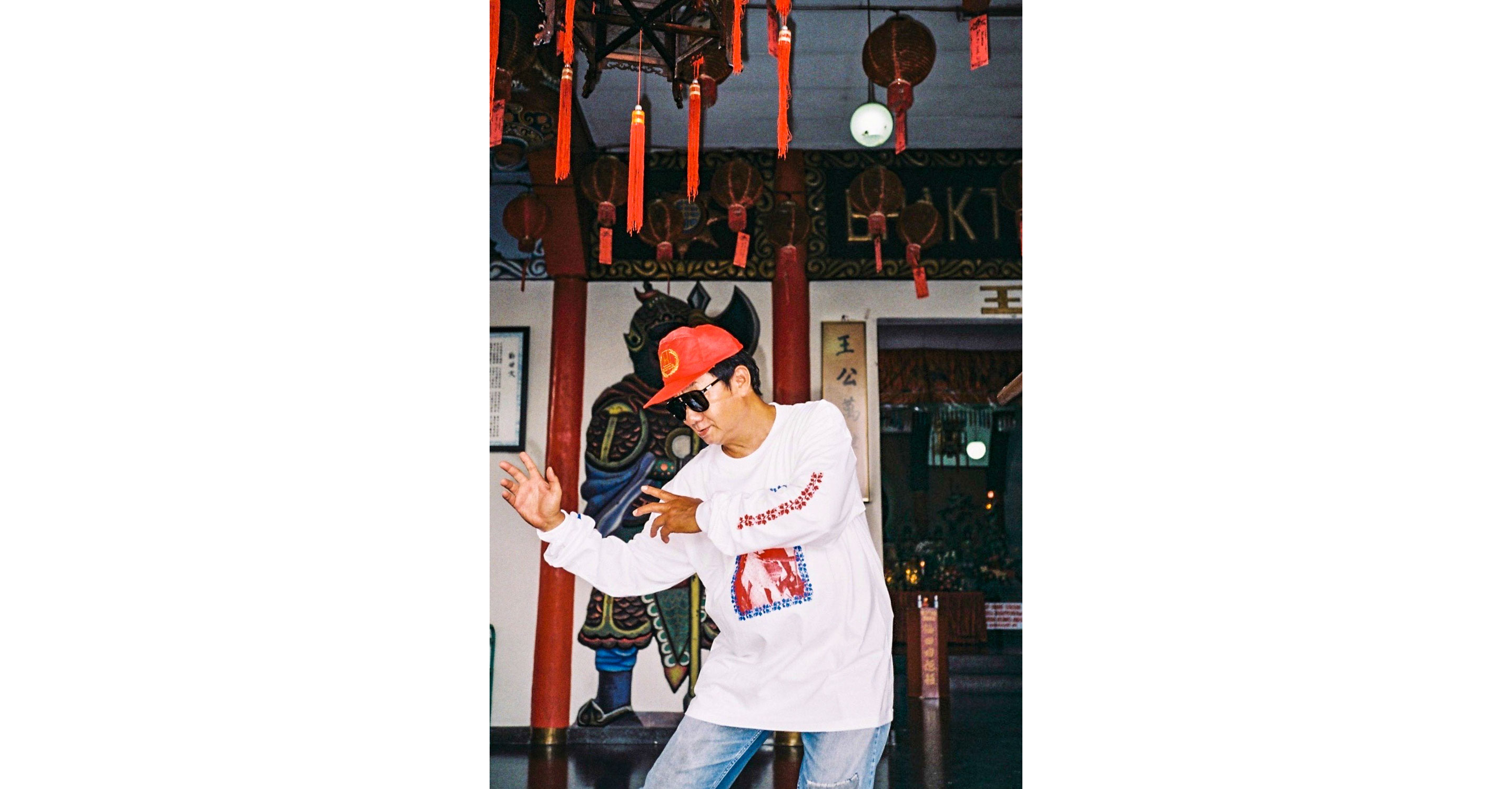 Paulus Supomo in sunglasses and red hat doing kung fu moves.