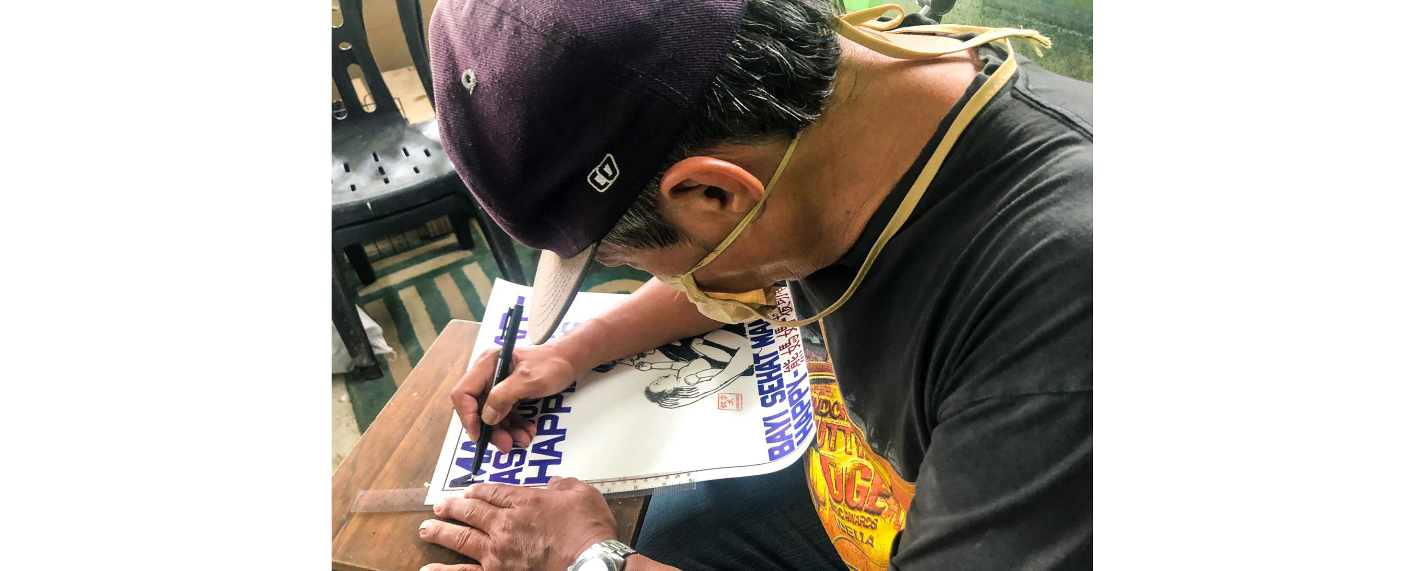 Paulus Supomo drawing his artwork with a black marker.