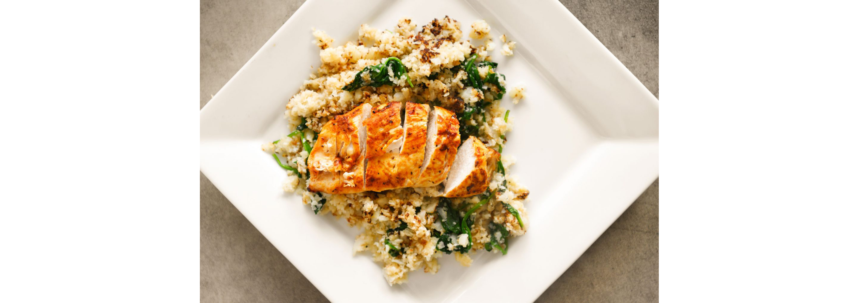 Sliced chicken resting on a bed of cauliflower rice.