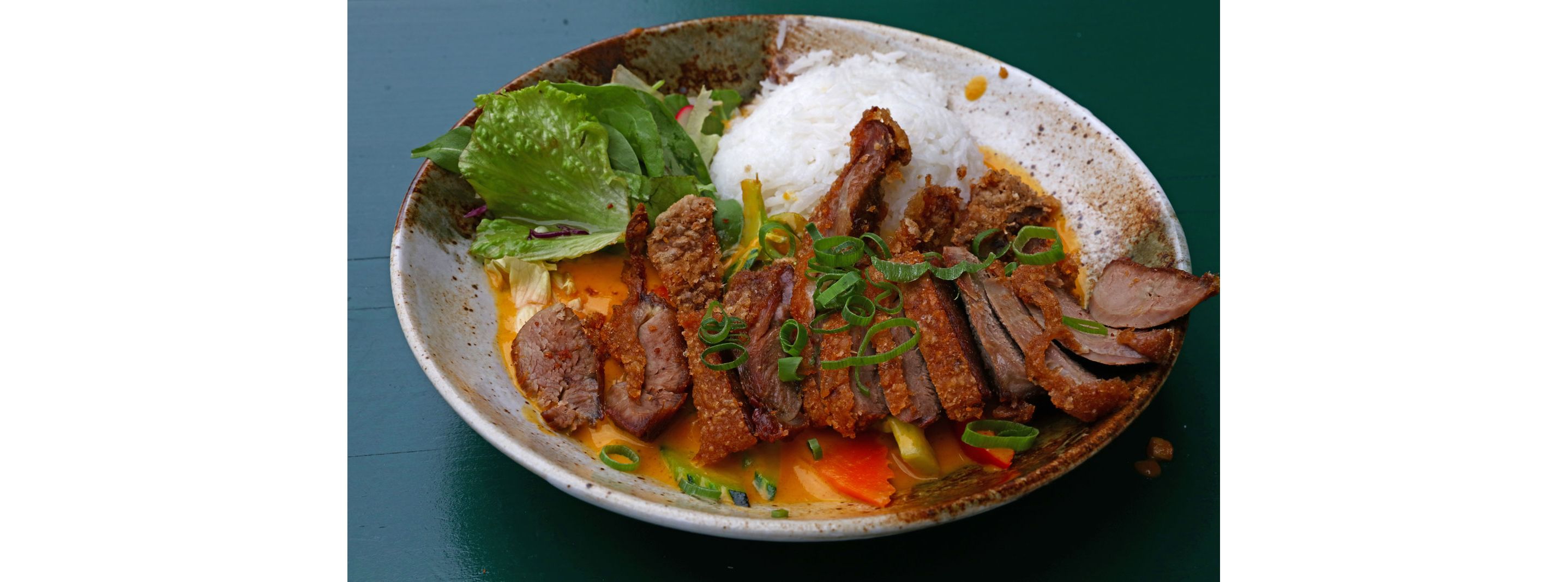 A plate filled with Caribbean curry, white rice and a side salad.