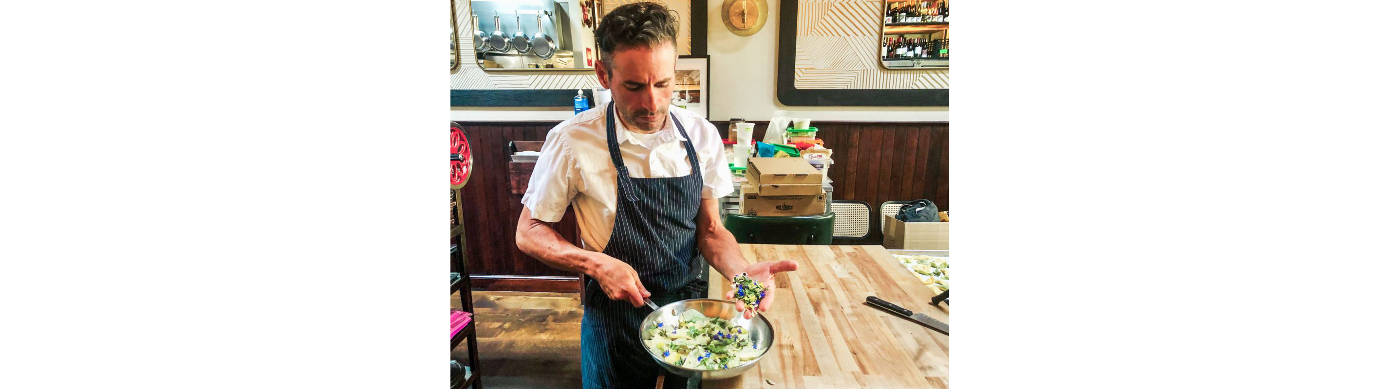 A chef working in edible flowers into a dish.