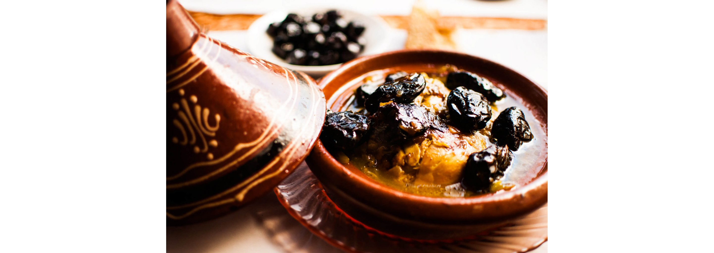 An open tagine filled with broth, cooked dates and other ingredients.