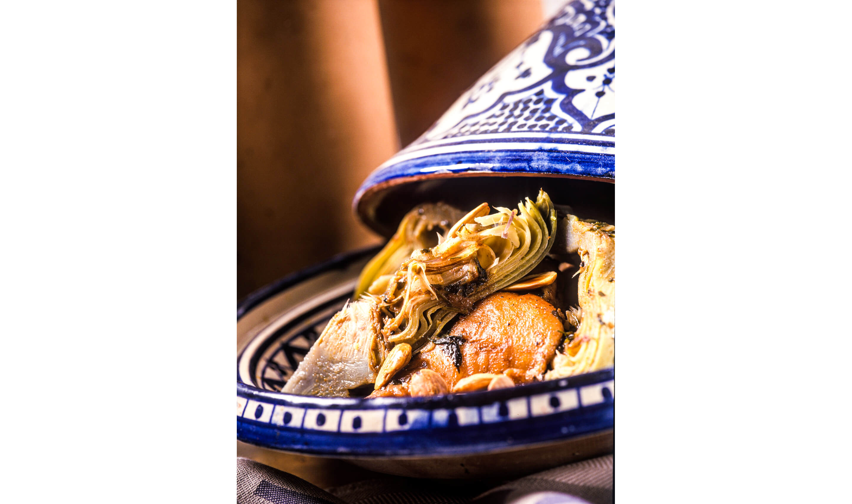 An open tagine filled with shredded artichokes, chicken and other ingredients.