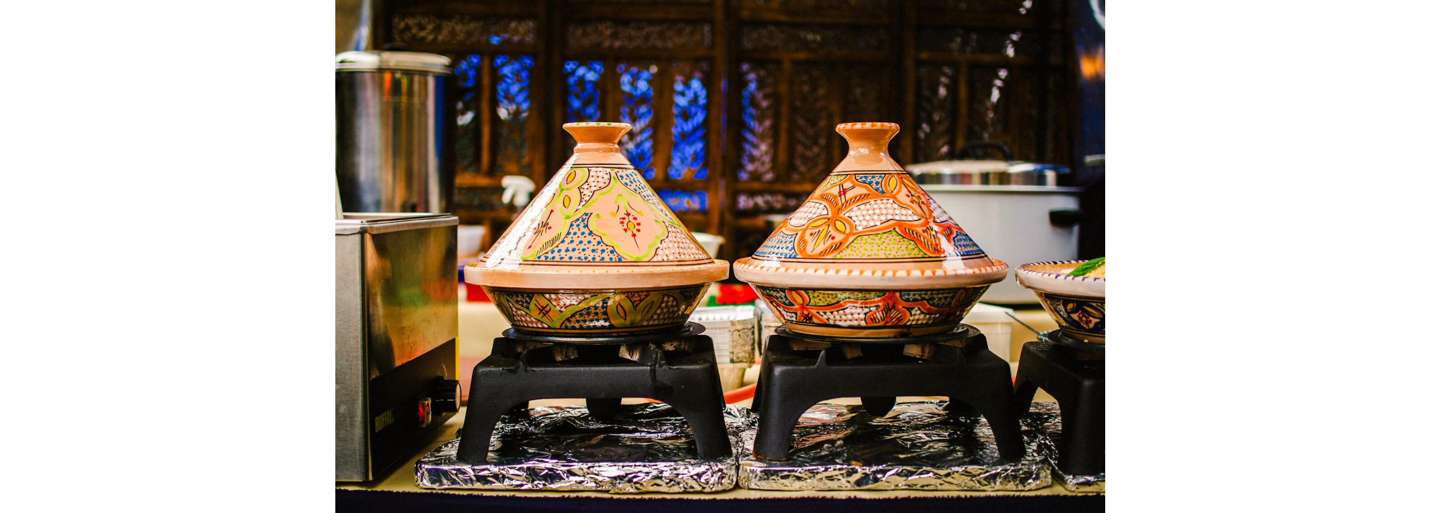 Two colorful, beautifully painted tagine pots set on top of black cooking grates.
