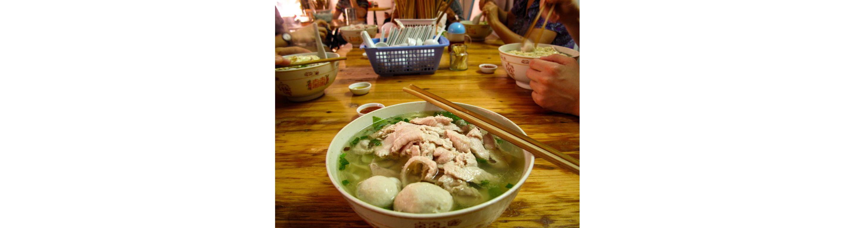 A bowl of soup accompanied by chopsticks.