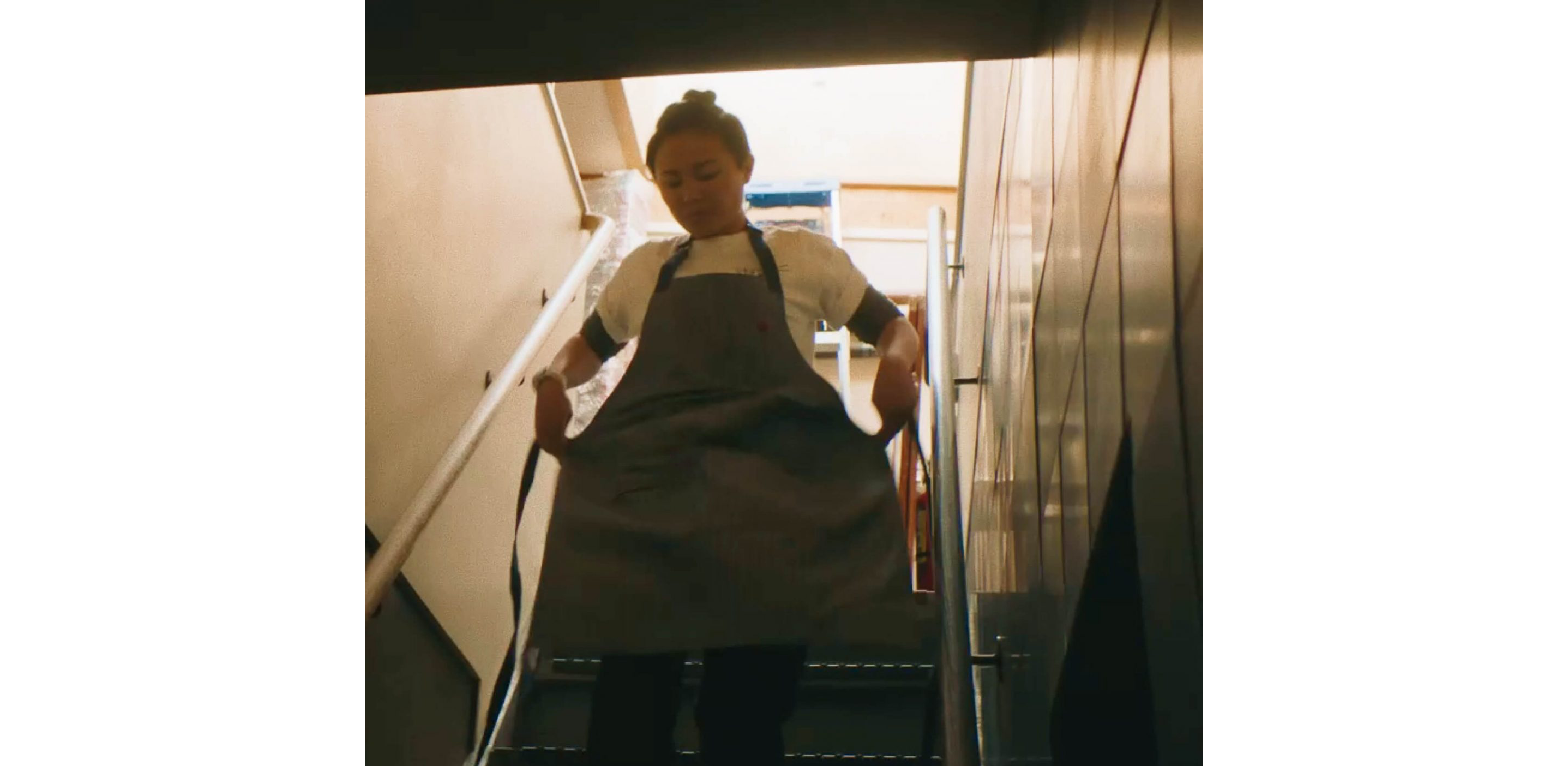 Marielle Fabie walking down a set of stairs, tying her apron on.