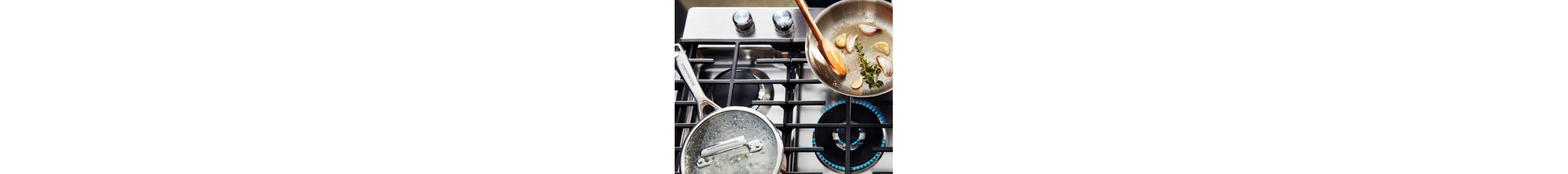 A boiling pot and pan of cauliflower on a gas stove.