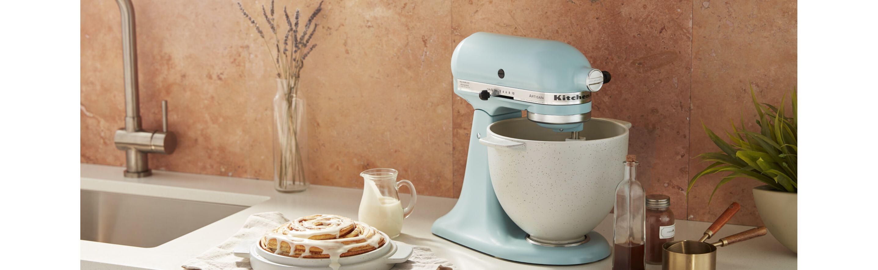 Glazed cinnamon bun beside a blue KitchenAid® Stand Mixer