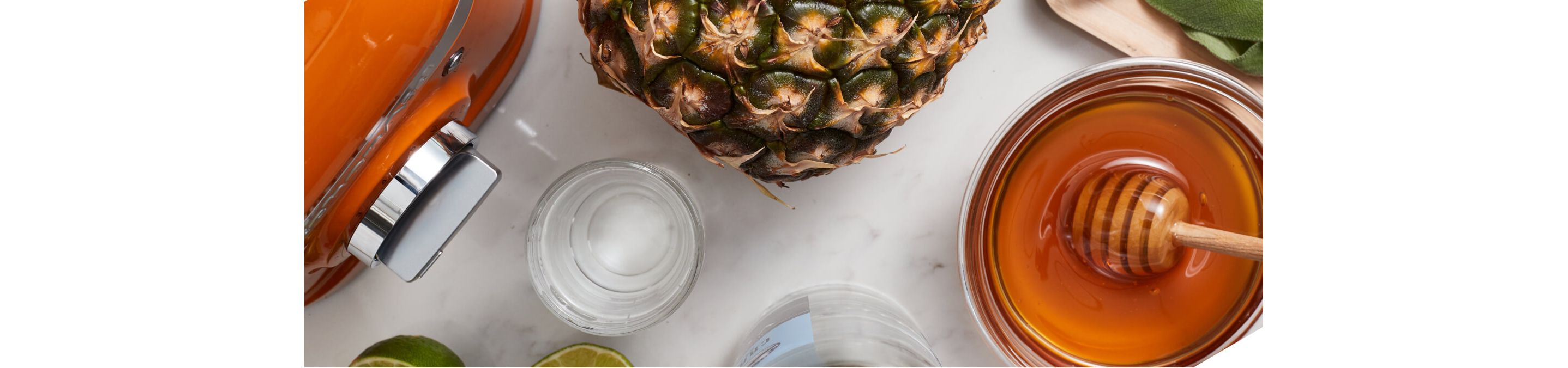 Overhead shot of KitchenAid® Honey colored blender surrounded by fresh pineapple, honey and limes.