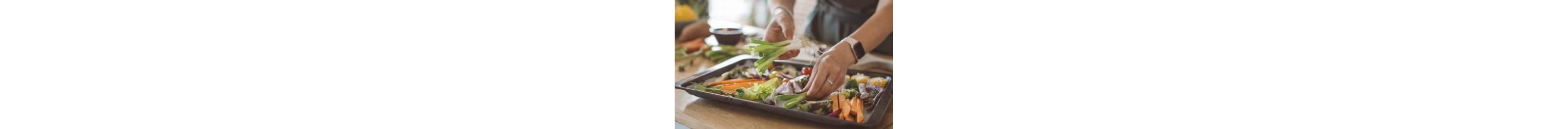 A person adding vegetables to a baking tray.