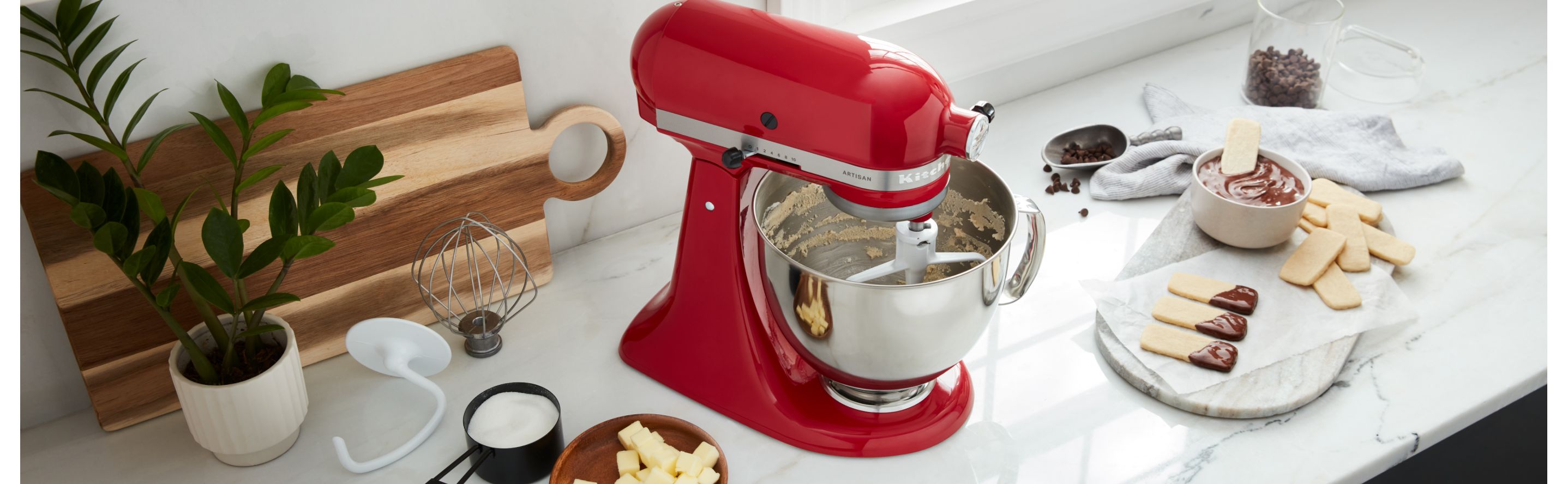 KitchenAid® Stand Mixer on a countertop surrounded by various sweet ingredients
