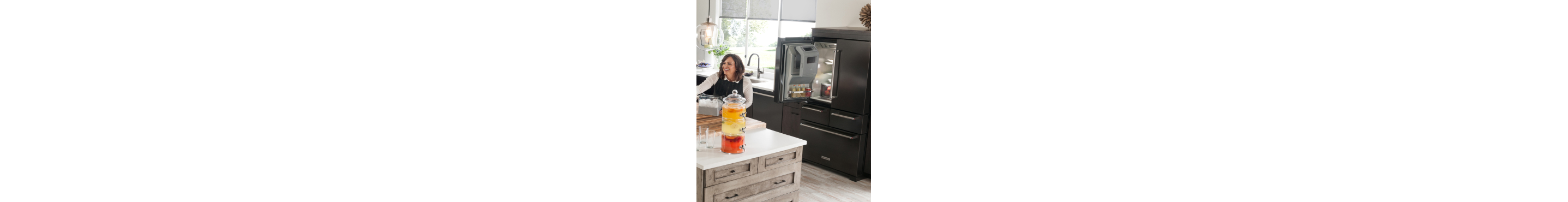 Person smiling at a kitchen island with an open refrigerator in the background